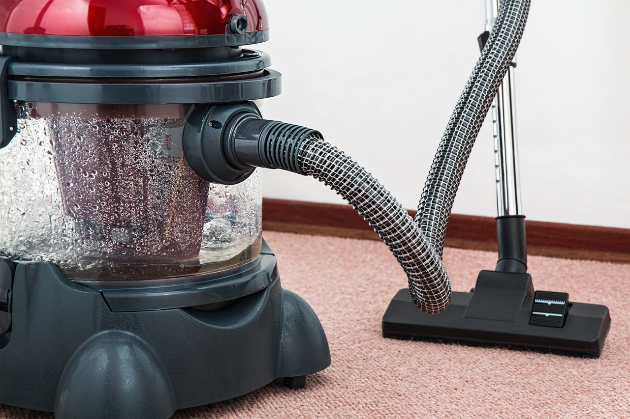 services-05 Close-up of a modern vacuum cleaner with water filtration on carpet floor indoors.