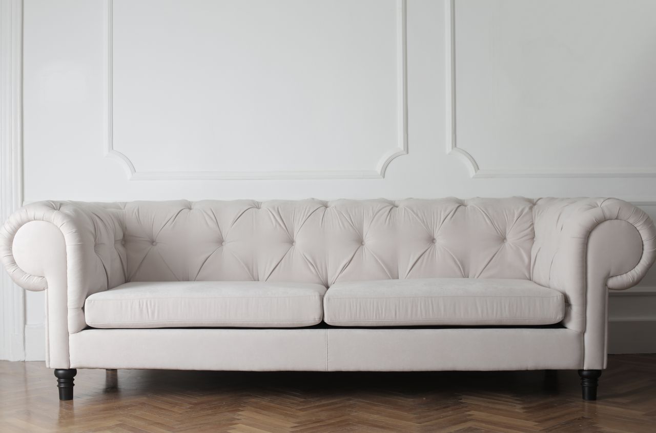 services-09 Luxurious white sofa in a modern minimalist interior with wooden flooring.